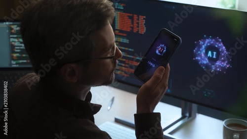 Over-the-shoulder view, of man holding smartphone, talking with AI chatbot app, asking questions, using artificial intelligence assistant for work and daily tasks on phone and computer. Space for text