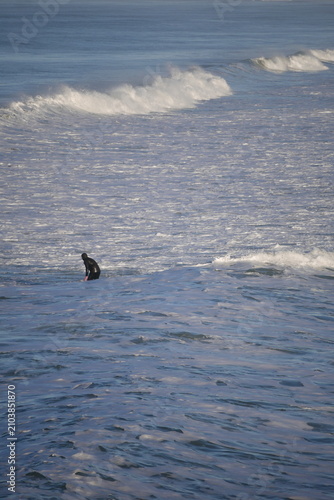 surfer paddling through cold water in winter Aotearoa New Zealand