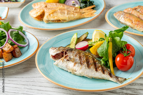 Whole grilled seabream served with colorful vegetables and lemon