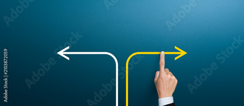 Businessman hand pointing at yellow arrow at crossroad, making decision and strategic choice concept.
