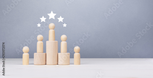 Top rating and business achievement concept with wooden human figures on a pedestal.