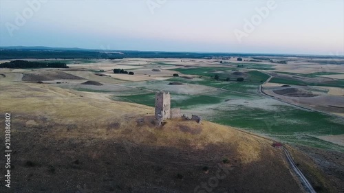 drone view of the historic medieval tower ruins of Torresavinan at sunset surrounded by vast agricultural fields in the Spanish countryside of Guadalajara