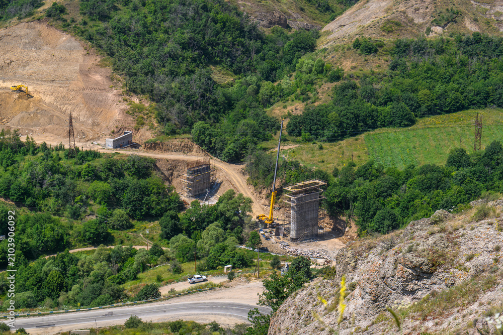 Obraz premium Construction site with crane and stone ruins in lush green valley