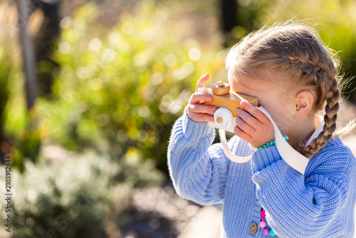 Child playing with toy wooden camera pretending to be a photographer