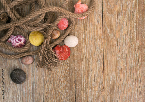 Rope and colorful stones on rustic weathered wooden board with background colorful weathered material vertical