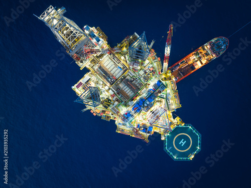 Aerial top view of offshore jack up rig and offshore platform during sunset for oil and gas exploration and production.