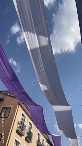purple and white fabric banners hanging over the streets of Brihuega during the annual Lavender Festival under a clear blue summer sky