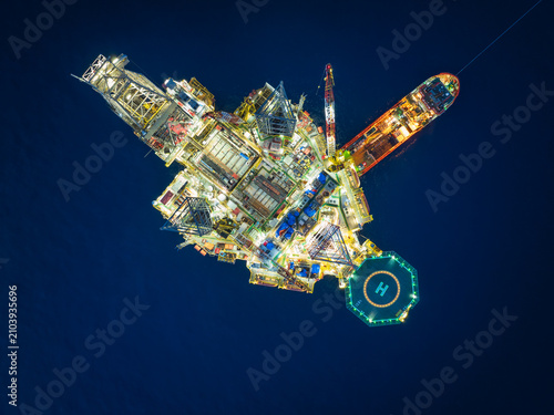Aerial top view of offshore jack up rig and offshore platform during sunset for oil and gas exploration and production.