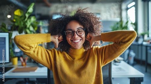 A cheerful woman with curly afro hair, wearing glasses and a yellow sweater,