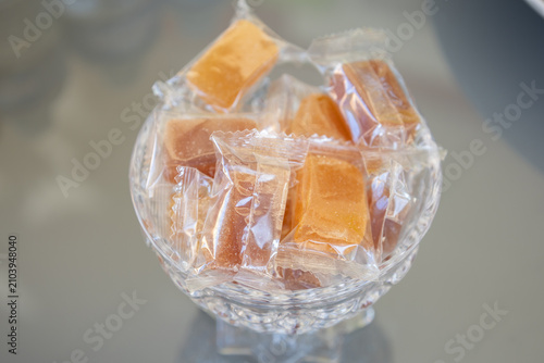 Bild auf Leinwand A bowl of wrapped caramel candies on a reflective surface