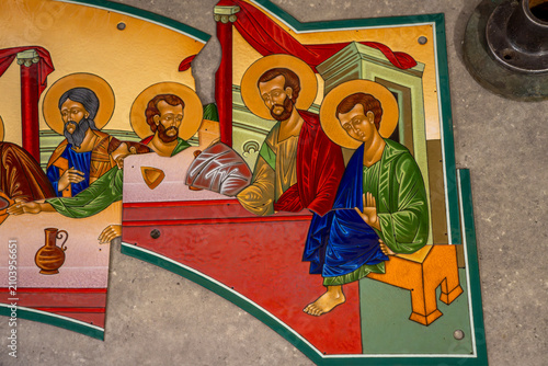 Foto Glossy metal plates coated with hot vitreous enamel layer depicting holy saints and biblical figures at the Last Supper table, lying on workshop floor during production process