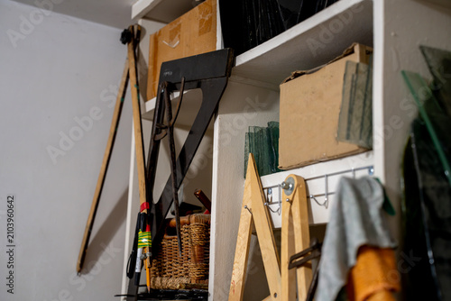 Canvastavla Large wooden proportional dividers, metal framing squares, and measuring instruments stored on shelves inside a craft studio workshop