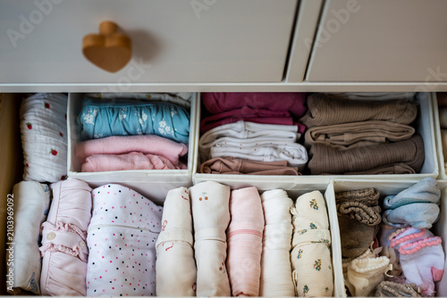 Neatly organized baby clothes arranged in dresser drawer using storage organizers, showcasing efficient wardrobe organization and newborn clothing storage at home.