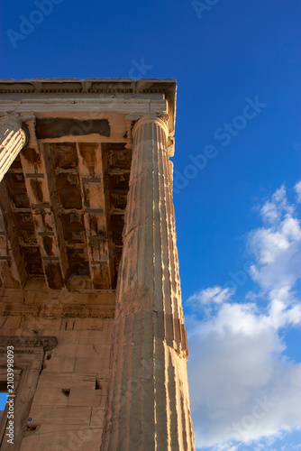 Ancient Greek ionic corner column and stone ceiling of the Erechtheion temple under a blue sky, Acropolis of Athens