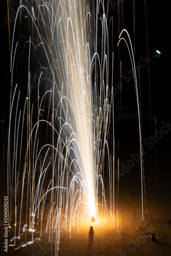 Slow shutter shot anar fountain firework during Diwali celebrations at night with trails of sparks with glowing flames and smoke.