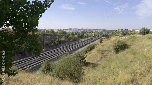 High speed passenger train traveling through the outskirts of Madrid on a sunny summer