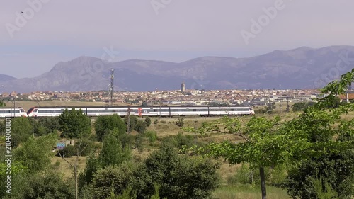 Commuter train crossing the Madrid outskirts with the Guadarrama Mountains in the background