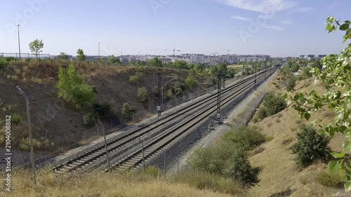 Modern high speed train passing along railway tracks with Madrid urban skyline in the background