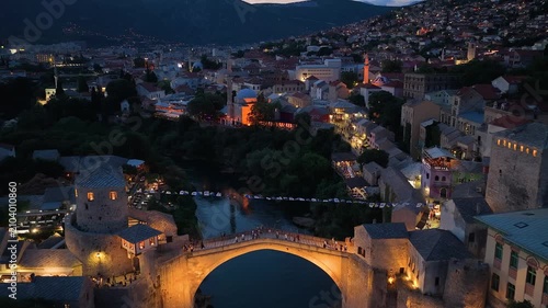 Mostar, Bosnia and Herzegovina - June 7, 2026: Drone flight above the illuminated Old Bridge toward the historic old town