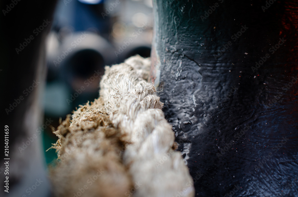 Obraz premium A mooring line passing through a fairlead on board the vessel. The fairlead guides the mooring rope during berthing and mooring operations, minimizing chafing and maintaining the correct lead angle