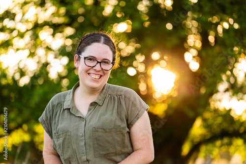 portrait of a young woman in her late twenties backlit by bokeh light through tree