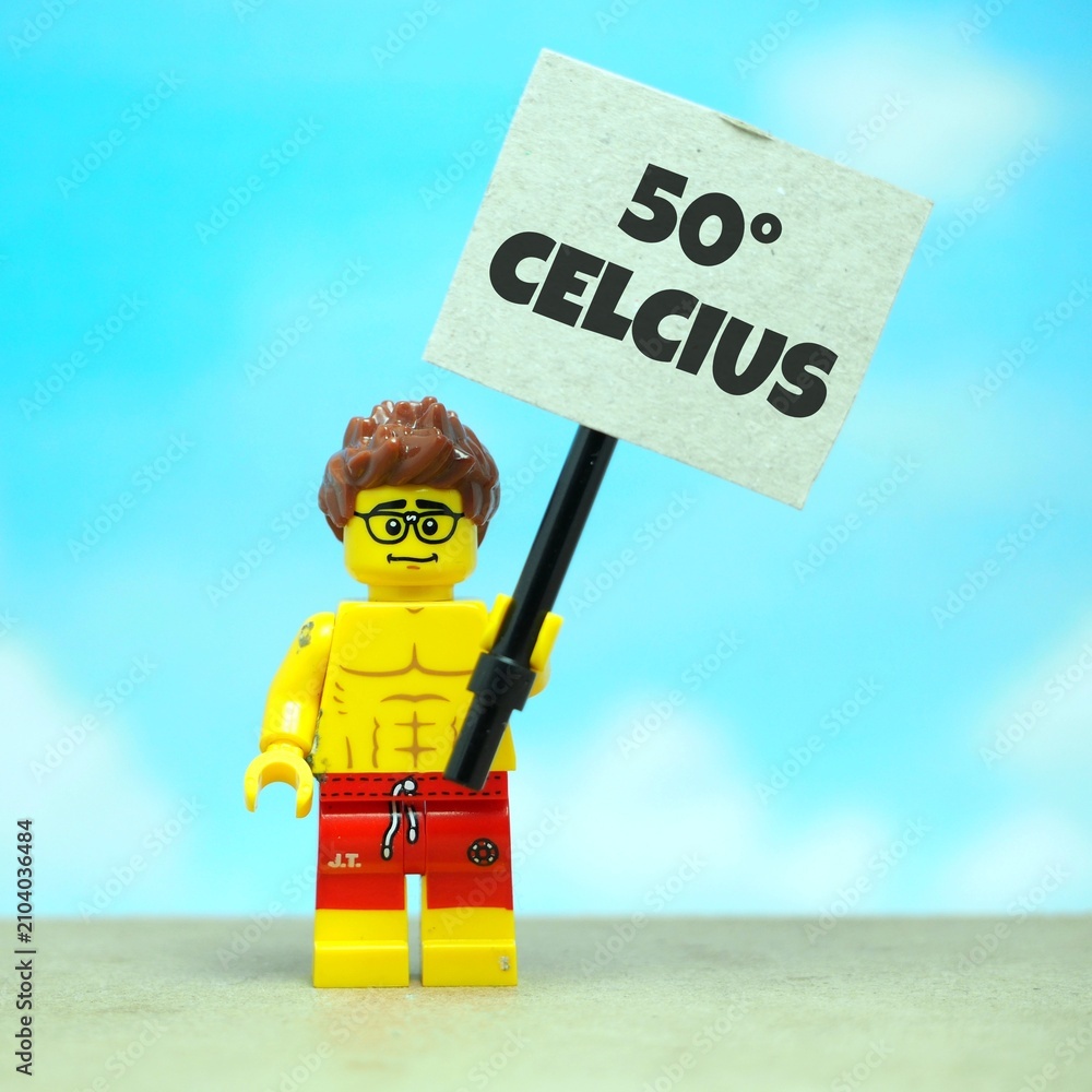 Fototapeta premium Indonesia - July 12, 2026 : Mini toy of action figure at outdoor with blur background. Miniature photography concept design. Minifigure of man male people hold 50° Celcius text at poster banner.