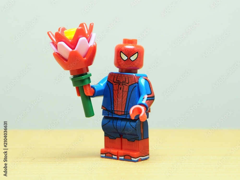 Naklejka premium Indonesia - May 27, 2026 : Mini toy of action figure at outdoor with blur background. Miniature photography concept design. Minifigure of Spiderman character hold bouquet of flower. Romantic person.