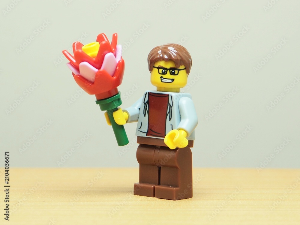 Fototapeta premium Indonesia - May 27, 2026 : Mini toy of action figure at outdoor with blur background. Miniature photography concept design. Minifigure of man character hold bouquet of flower. Romantic person.
