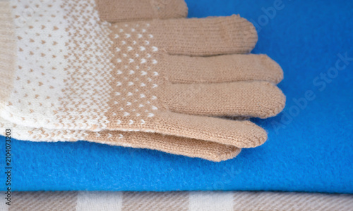 Light beige knitted gloves on a blue scarf