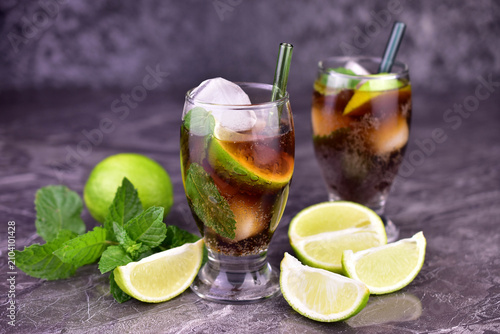 Sticker Cuba Libre cocktail with lime, rum, mint, and ice on a black background