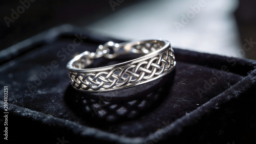 Close-up of intricate Celtic silver knotwork jewelry on dark velvet.