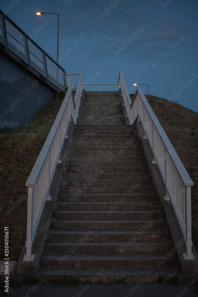 Fototapeta premium Long concrete staircase with white railings against twilight sky