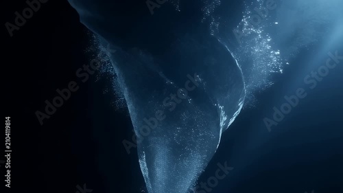 Dramatic water vortex swirling in deep blue ocean dark background with light rays