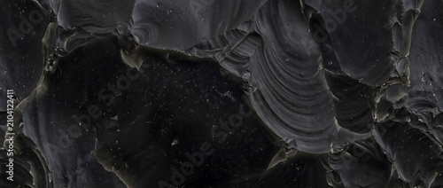 Фотография Black stone texture displaying a polished obsidian flint mineral surface with sh