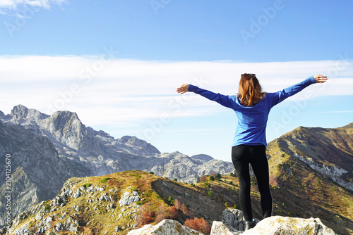 Bild auf Leinwand Hiker spreads arms wide atop rocky Volusnica summit in Prokletije during autumn