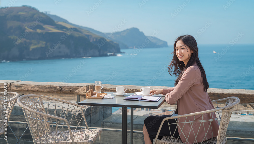 Obraz premium 一人旅の女性が海辺カフェで手帳を開く写真
