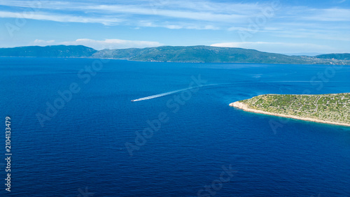 Fényképezés A speedboat carves through the deep blue Adriatic Sea, passing a verdant island under a clear summer sky