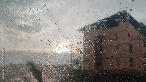 raindrops on the windshield of a car with the house in the background