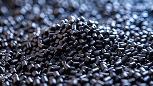 Close up of black plastic granulate on dark background highlighting polymer resin materials for injection molding processes