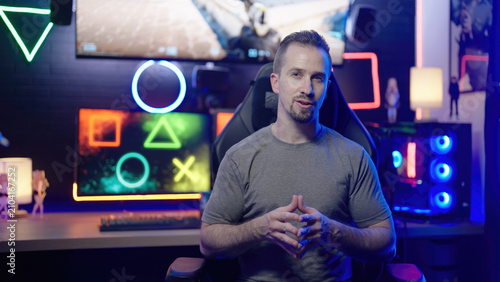Gamer influencer enthusiastic explaining to camera in gaming cyberspace room