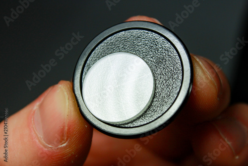 Фотография Microscope eyepiece reticle with crosshair held between fingers for inspection, calibration and precision optical measurement