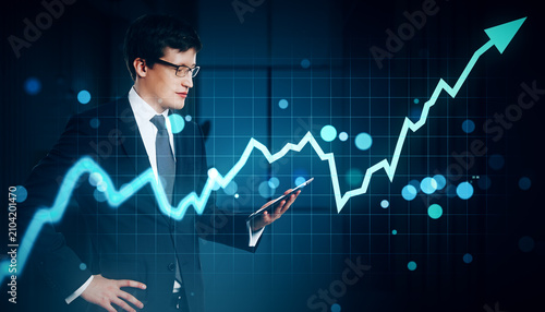 Businessman in glasses holding tablet and analyzing rising green financial gr...