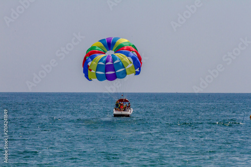 Принти на полотні Horizontal eye level wide shot of a speedboat pulling a colorful parasail with t