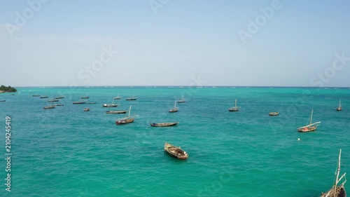 Aerial top view traditional fishing boats in turquoise water of Kiwengwa beach, Zanzibar, tropical landscape with white sand and clear Indian Ocean, Tanzania, drone shot