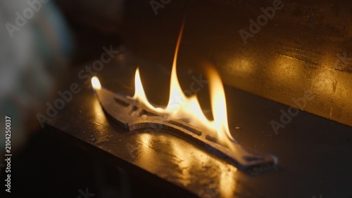 Fotografie A blacksmith removes a red-hot knife blade from a furnace, immerses it in an oil bath, and it ignites in flames during the metal quenching process
