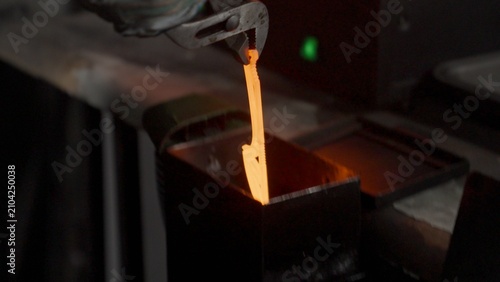 Photography A blacksmith removes a red-hot knife blade from a glowing furnace and immerses it in an oil bath during the quenching process