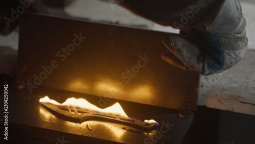 Tableau sur toile A blacksmith quenches a red-hot knife blade burning with flames during the metal quenching process