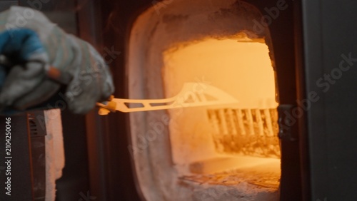 Canvas Print A blacksmith removes a red-hot knife blade from a furnace, immerses it in an oil bath, and it ignites in flames during the metal quenching process