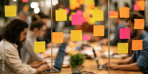 People working at desks with colorful sticky notes on a glass wall