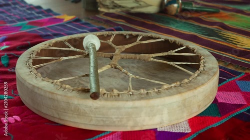 A shamanic leather drum or tambourine lies on the floor